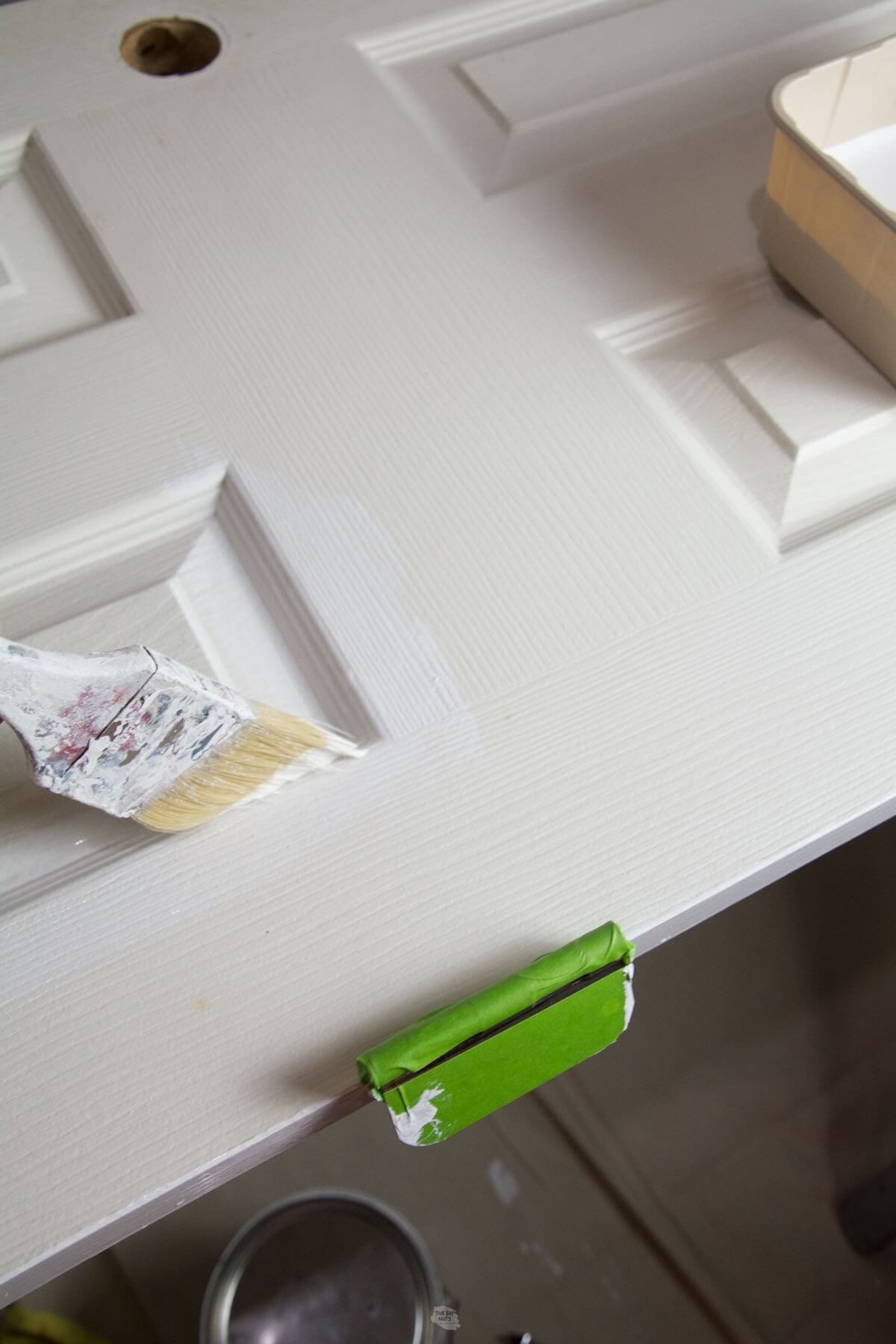 paint brush painting white door with fresh coat of white.