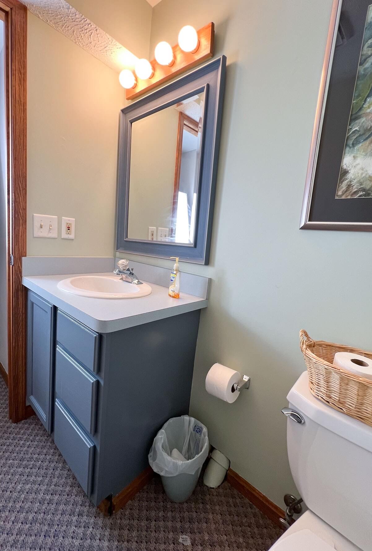 dusty blue painted bathroom vanity with blue laminate counters.
