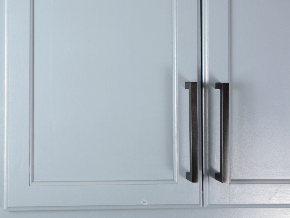 large black hardware pulls on painted blue gray cabinets.