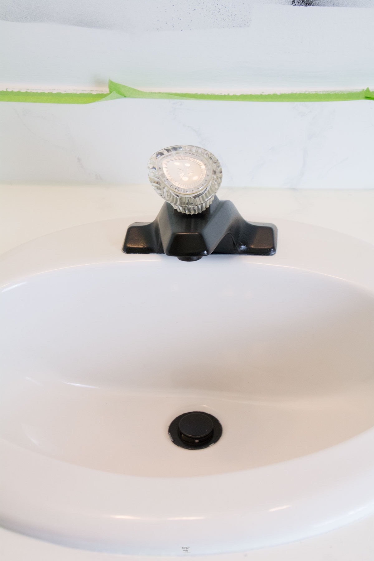 black painted faucet and drain on white ceramic sink.