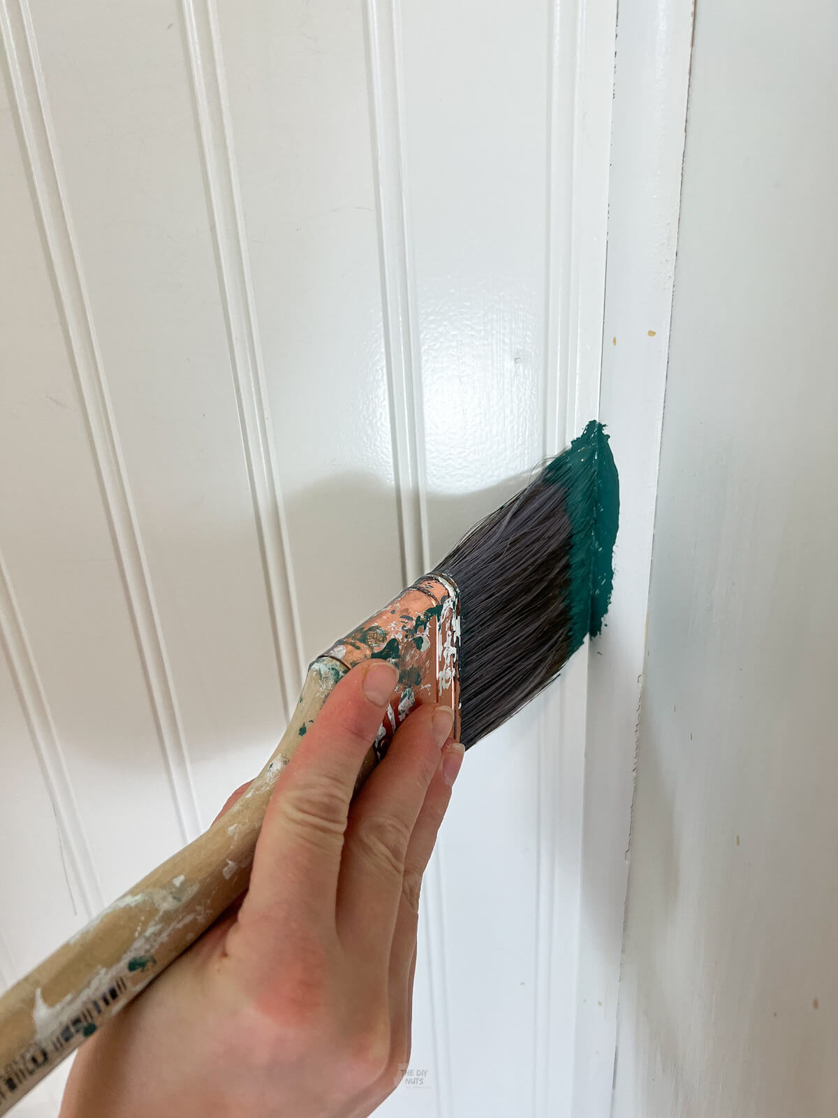 2.5" synthetic brush with green paint painting small areas of closet cubby.