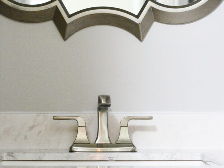 sink faucet on counters with part of silver mirror showing in bathroom.