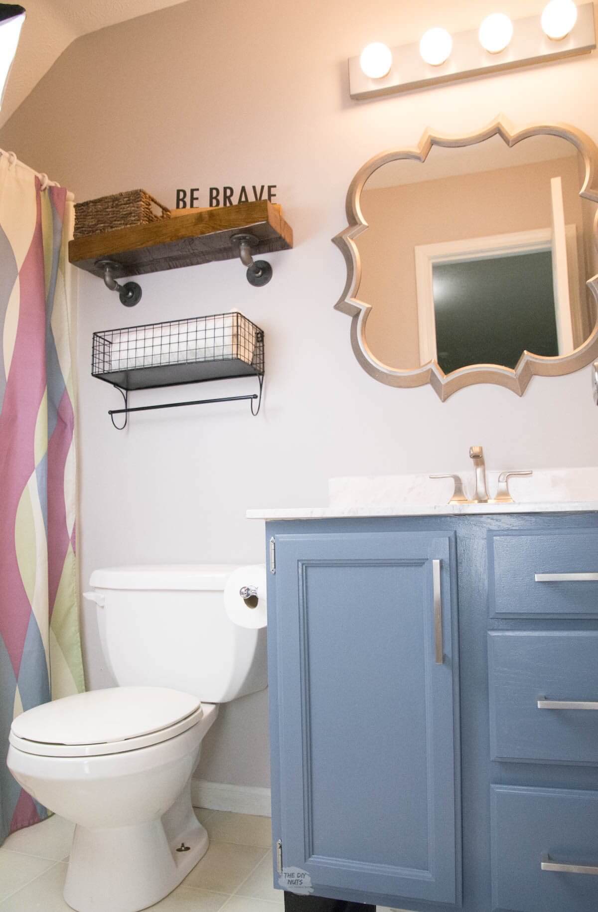 small bathroom with painted cabinets, shelves and organic mirror.