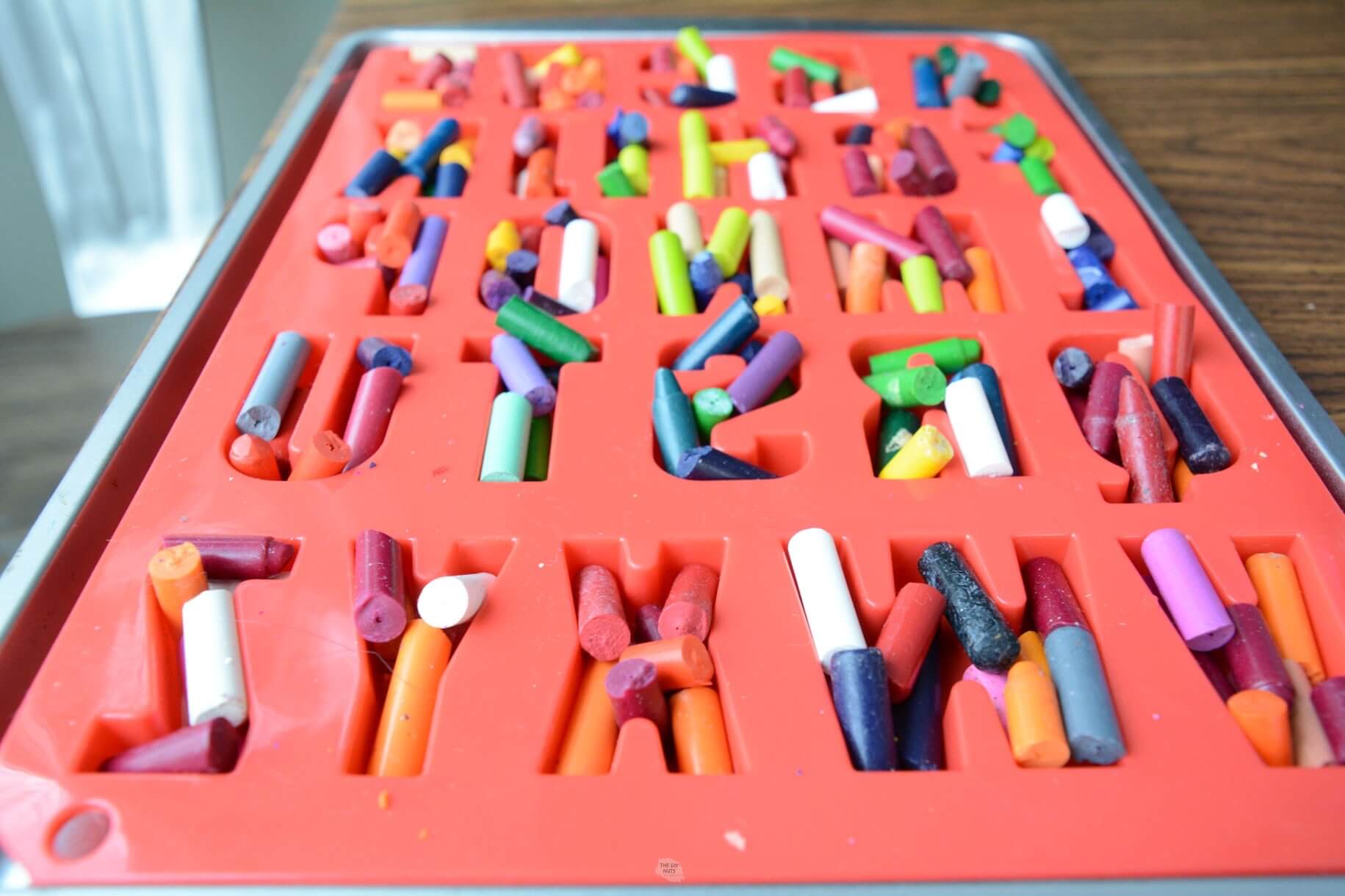 side view of silicone letter molds with broken crayons overflowing the letters.