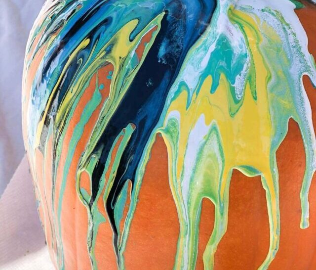 Paint pour pumpkin with blue, teal, yellow, white and black marble effect.
