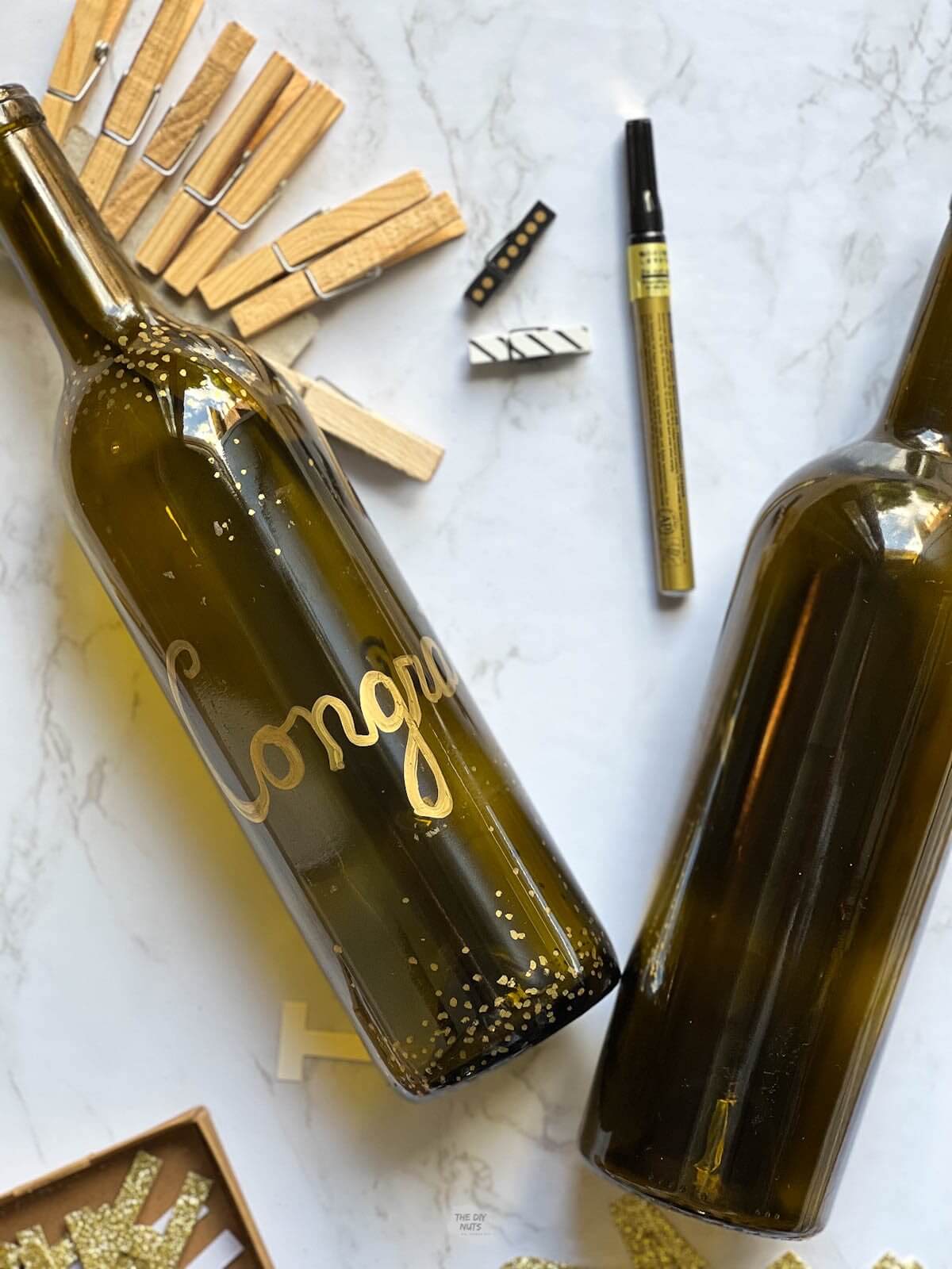 wine bottle with congrats on it with clothes pins and gold marker.