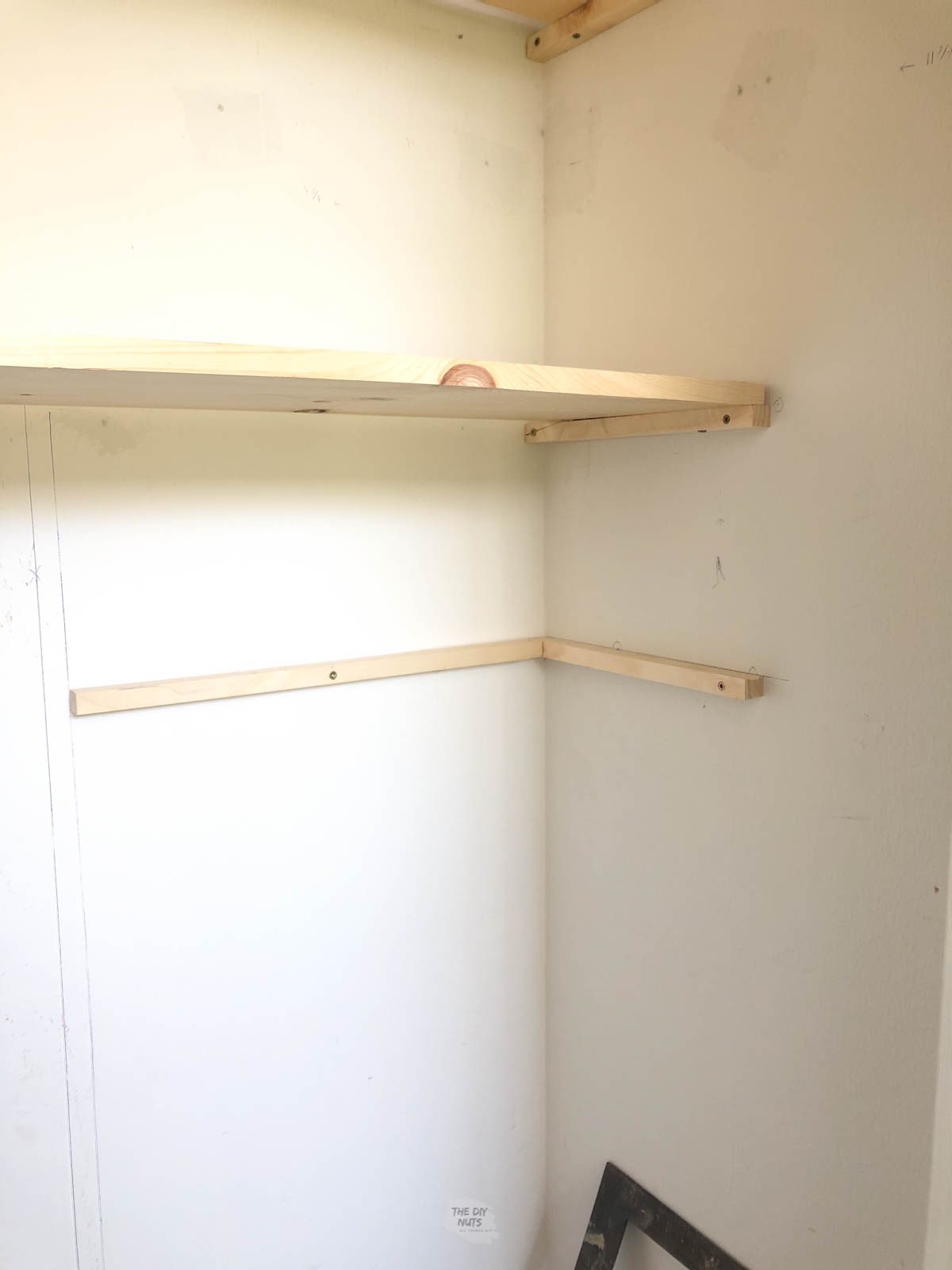 wooden corner bracket shelf under wooden closet shelf.