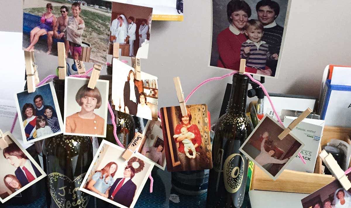 pictures of a family in a diy wine bottle photo holder for anniversary party.