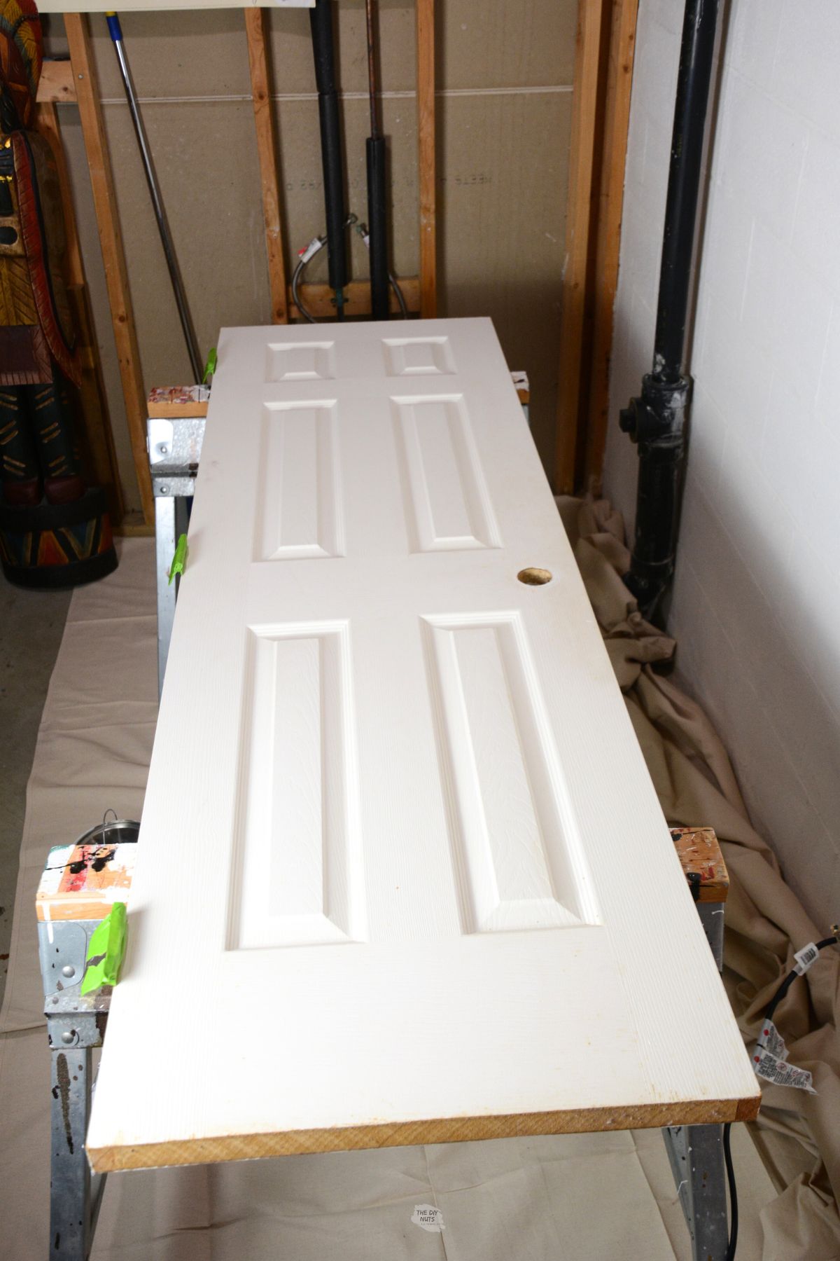 white/cream colored door on sawhorses in basement corner.
