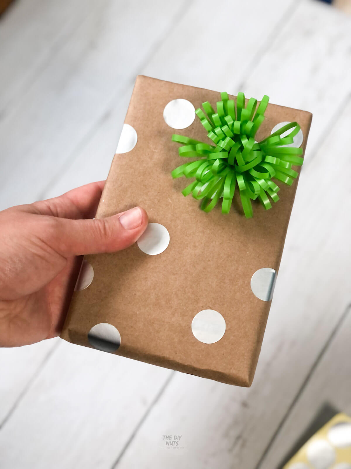 brown paper wrapping with circles and green bow on shiplap.