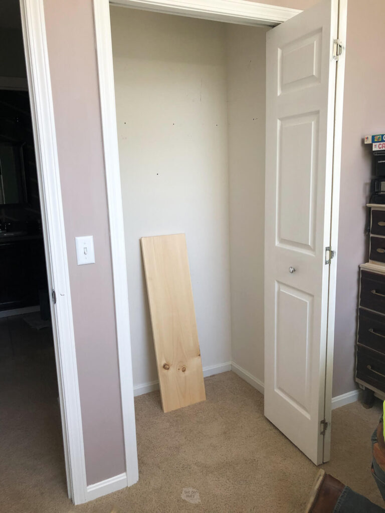 empty closet before DIY shelves with wood resting in closet with door open.