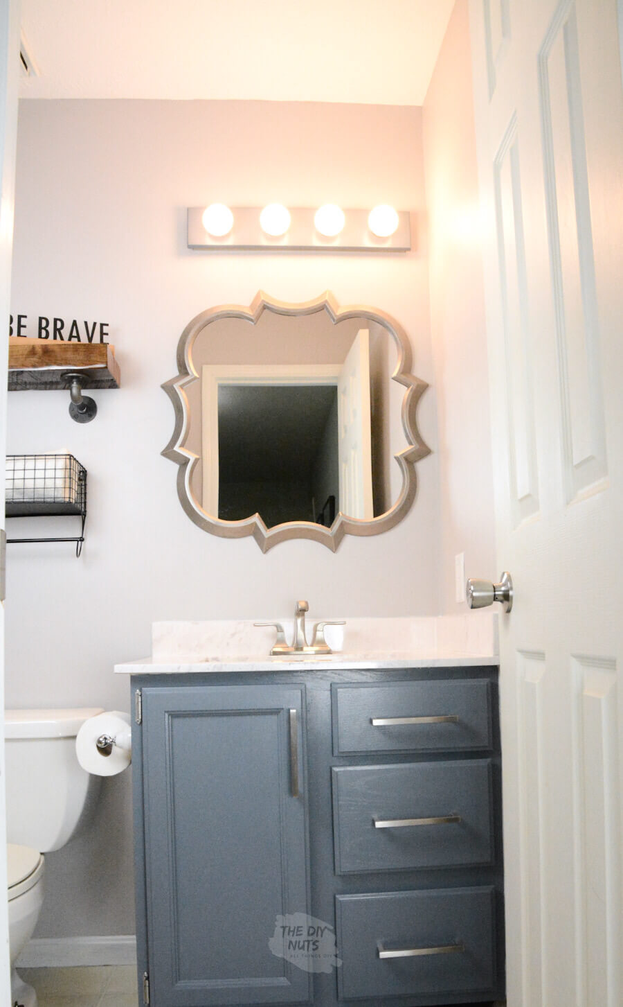 grayish painted walls with charcoal blue painted cabinets with fun shaped silver mirror