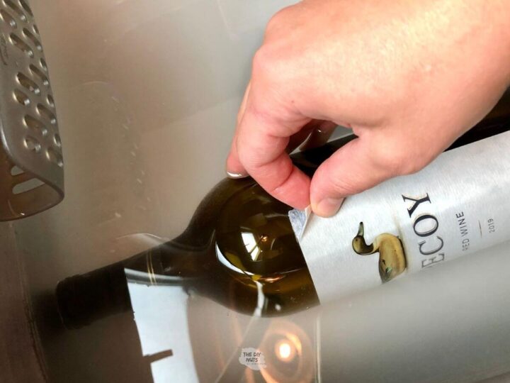 wine label being removed by hand and bottle soaking in baking soda