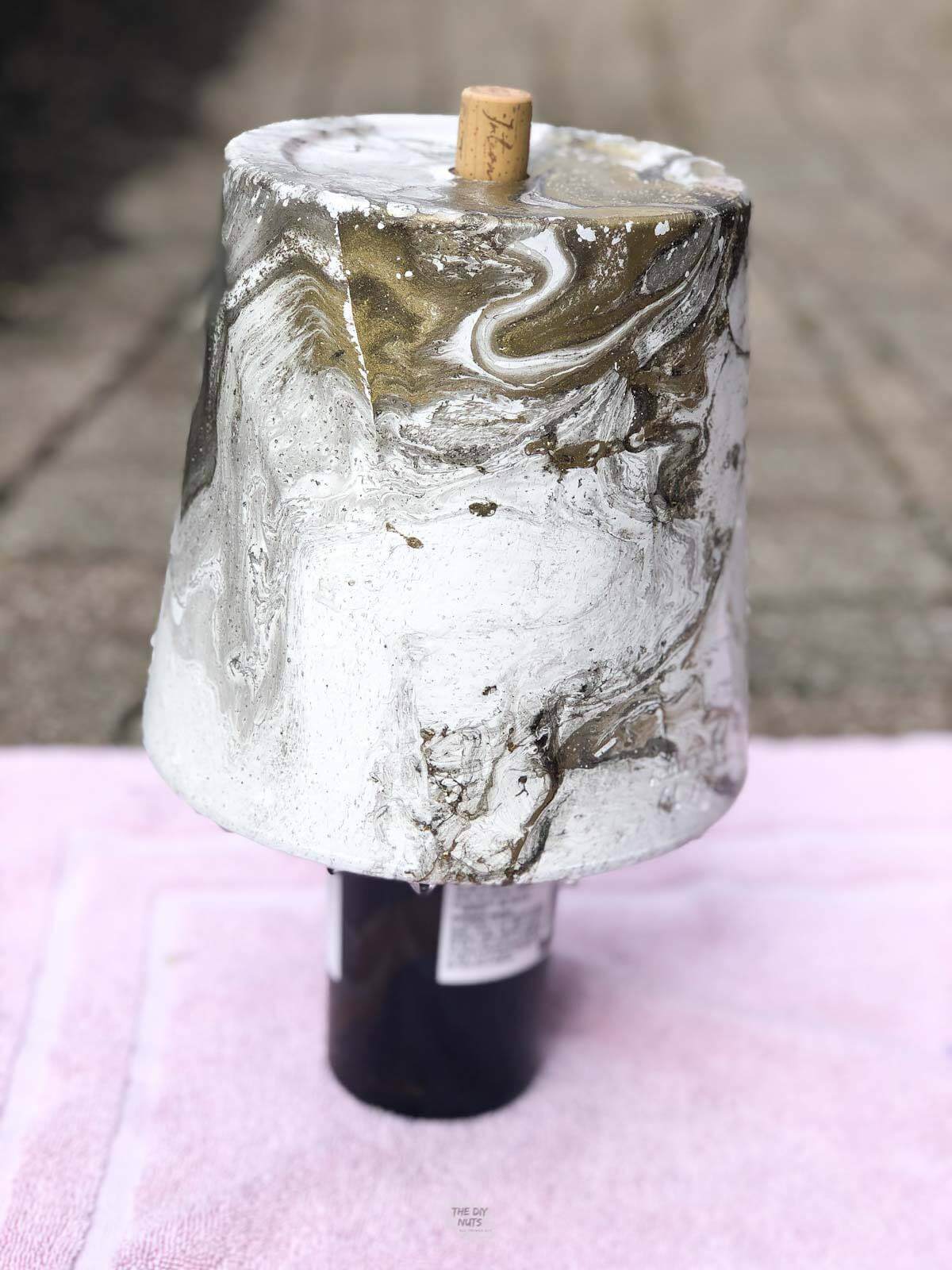 DIY marbled pot resting upside down on wine bottle.