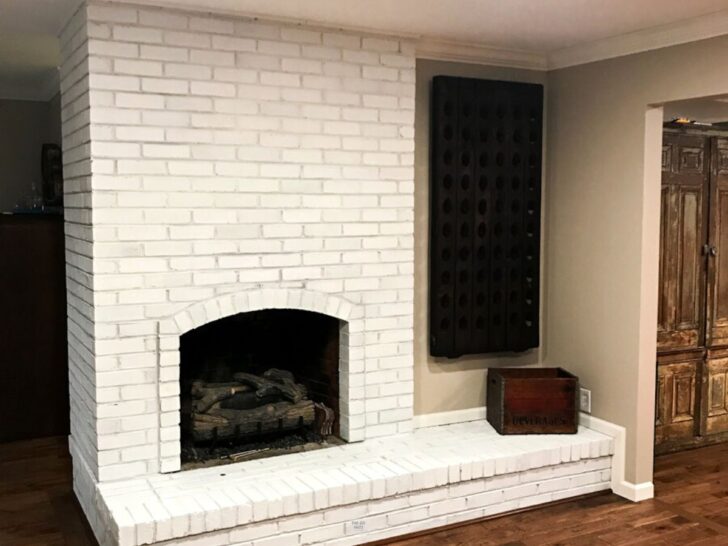 large white painted brick fireplace with wall wine rack on wall.