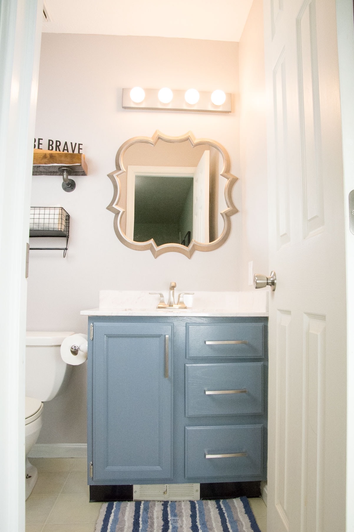 painted bathroom vanity cabinets with mirror and painted light fixture.