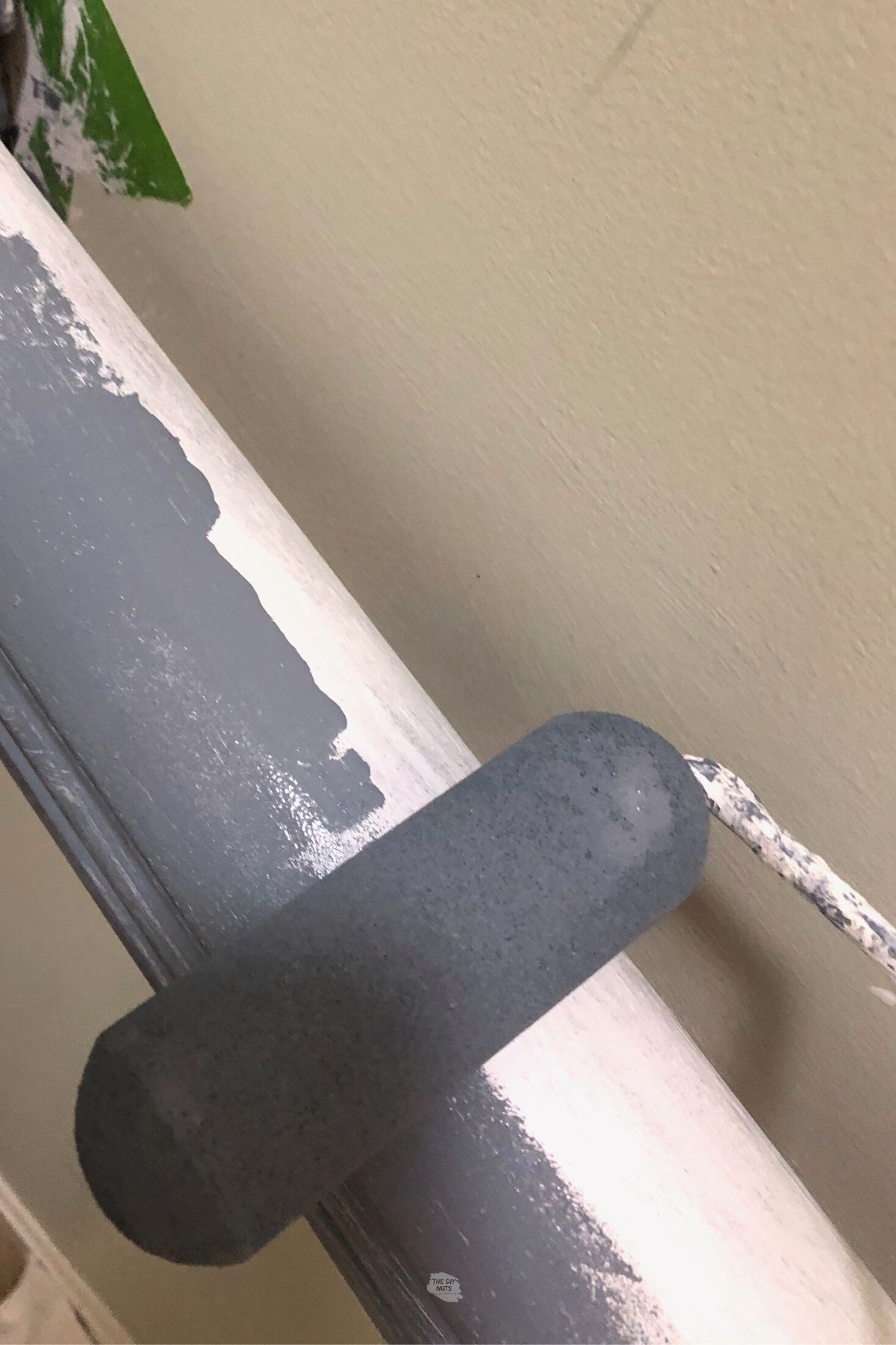 small foam roller adding blue gray paint to banister.