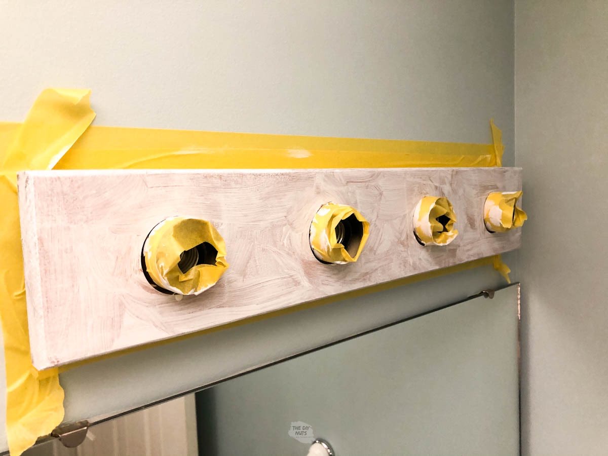 yellow painter's tape on bathroom light fixture with primer.