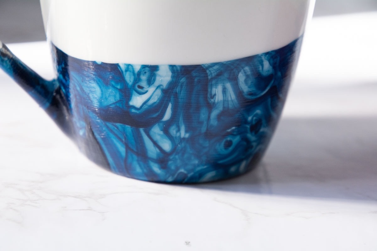 bottom of white mug with blue marbled paint on it.