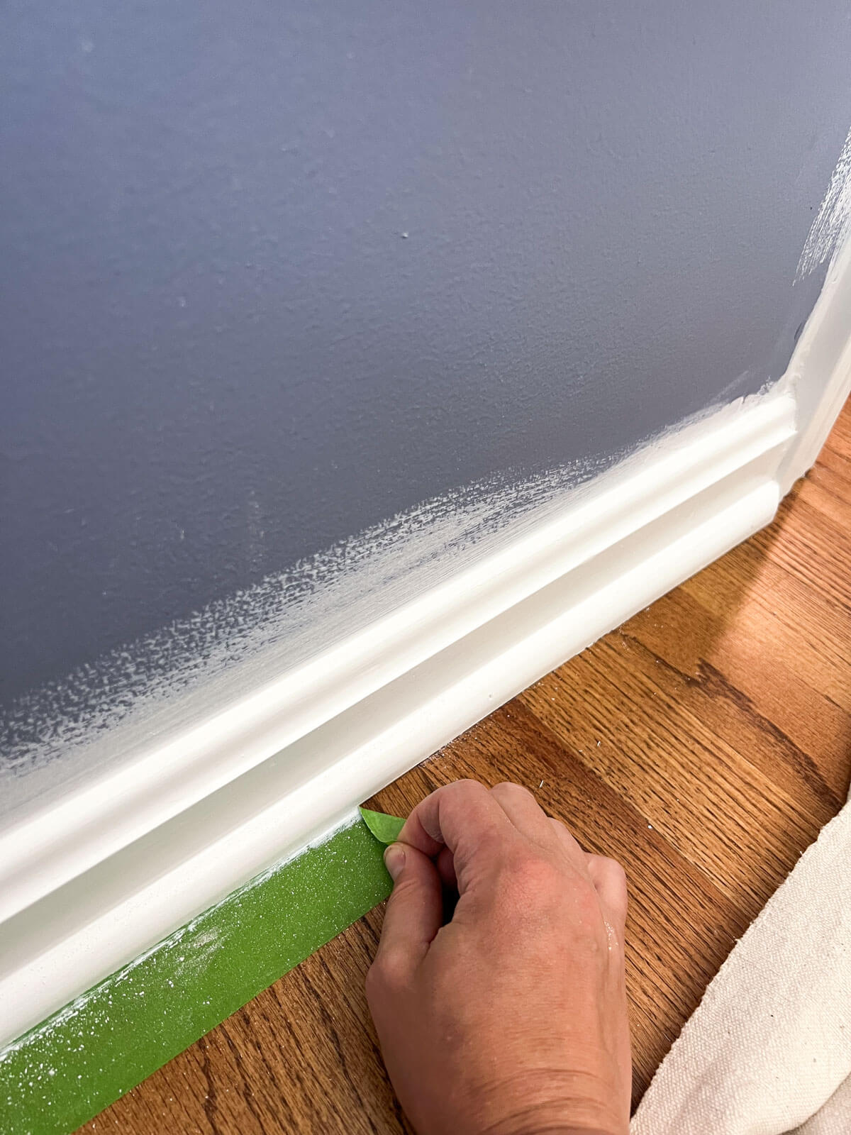 hand pulling green painter's tape away from trim.