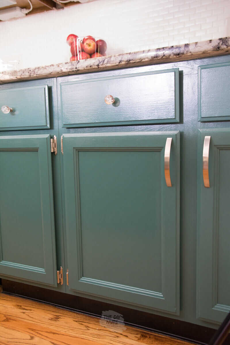 green painted kitchen doors and cabinets with polished nickel hardware and glass knobs.