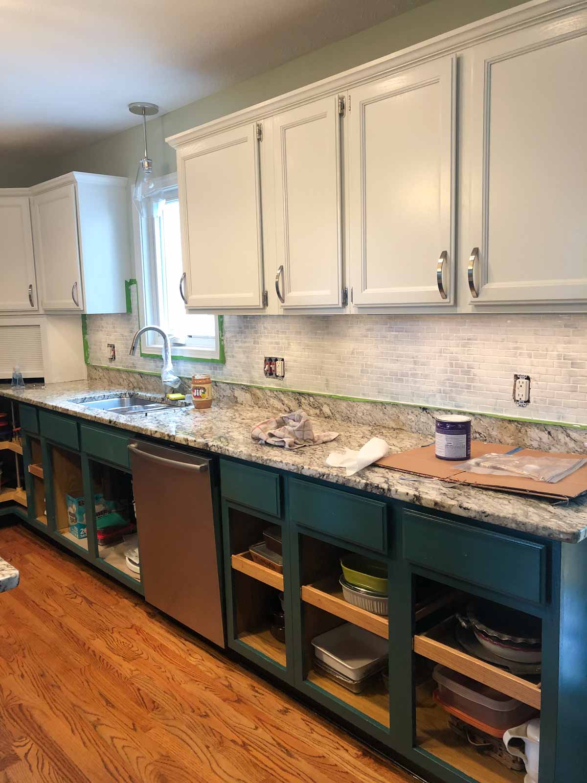 kitchen with painted cabinets and backsplash with paint supplies on contertops.