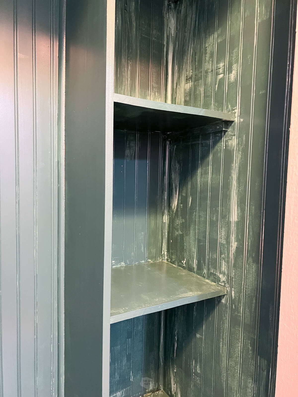 wood shelves with first coat of green paint on them.