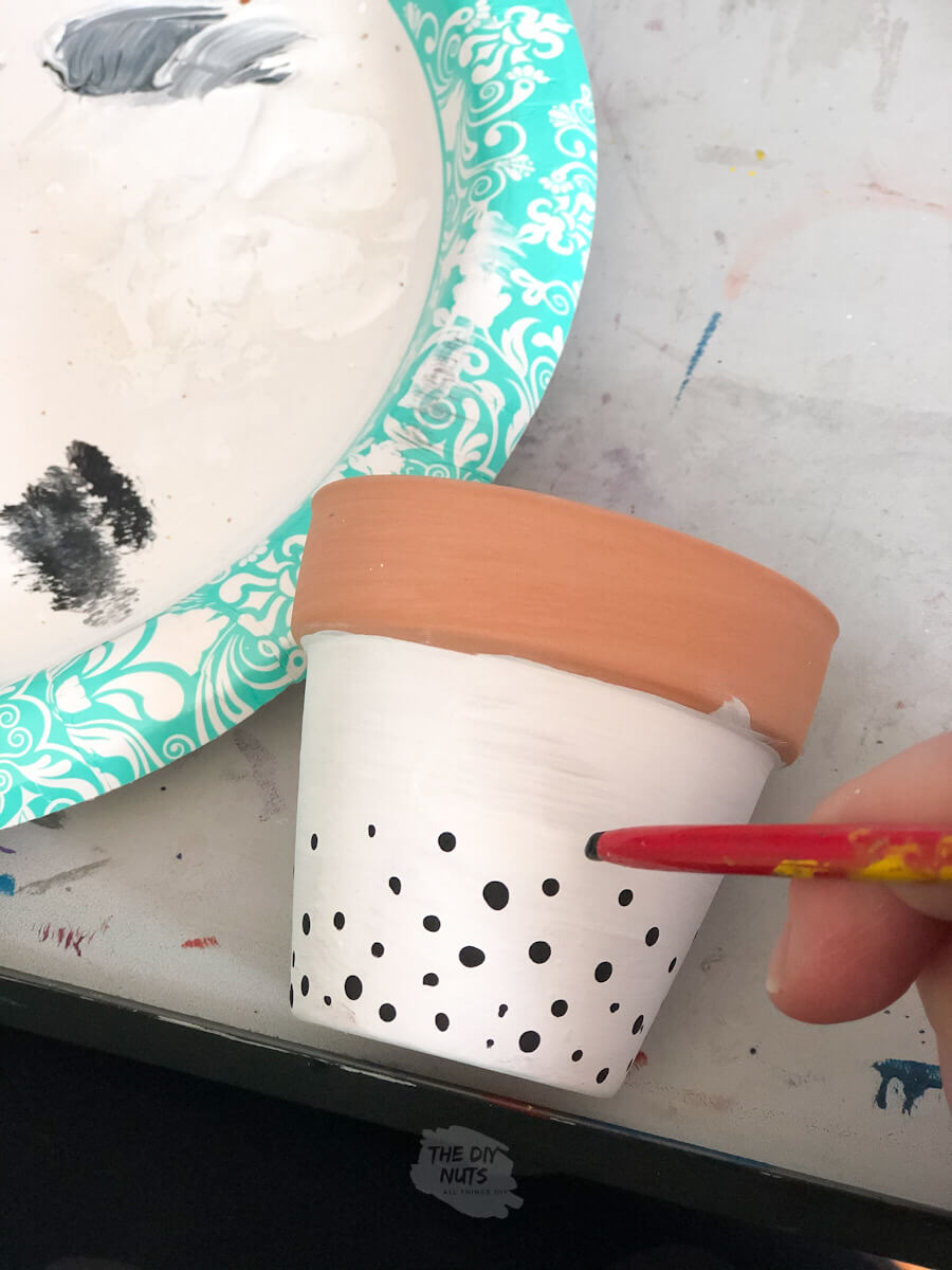 the end of a paint brush used to make dot design on terracotta pot