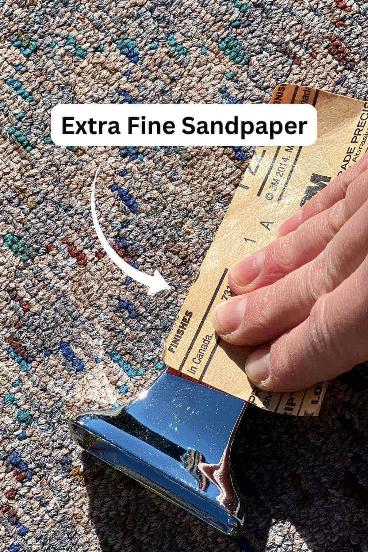 hand using sandpaper on metal toilet roll holder.