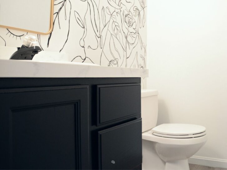 tricorn black painted bathroom cabinets with black and white accent wall and part of gold mirror.