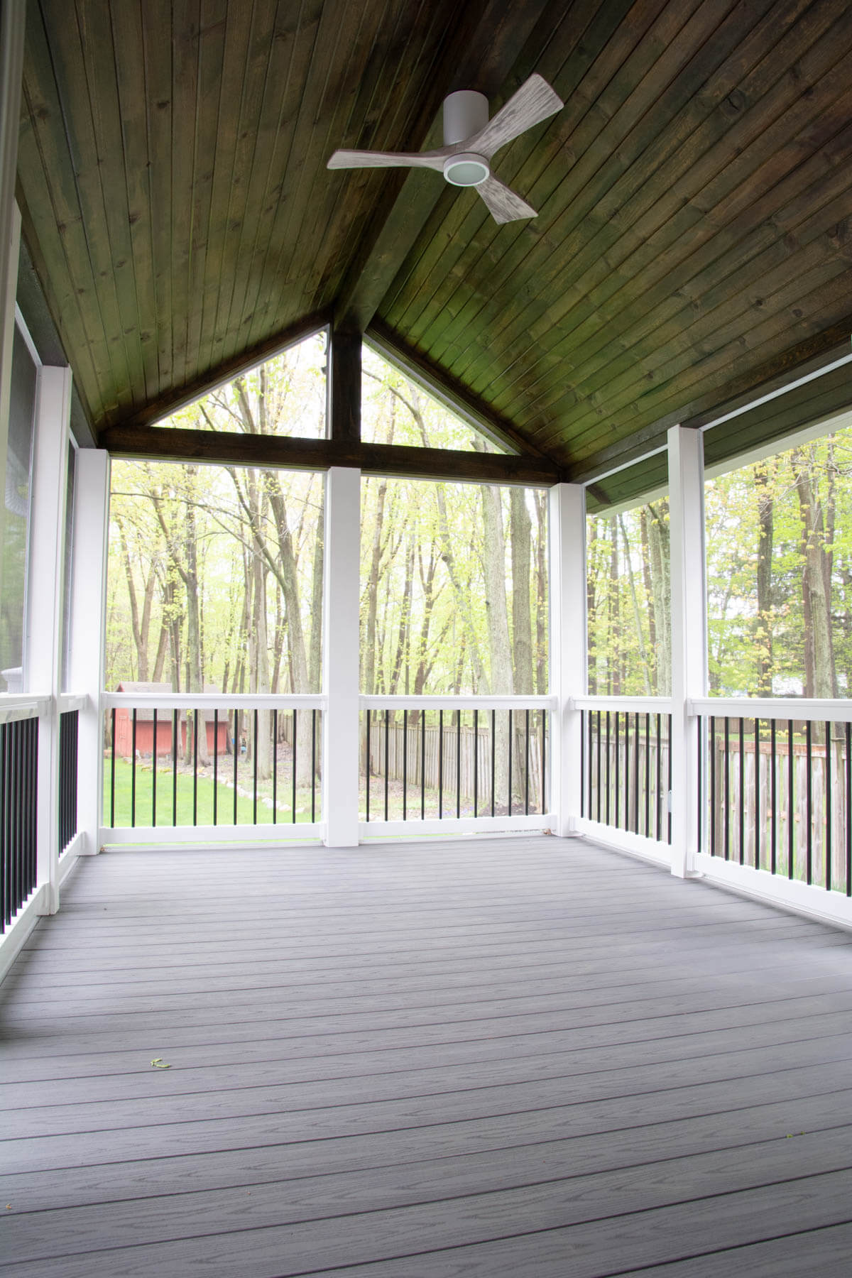gray composite decking with black and white rails and wood ceiling.