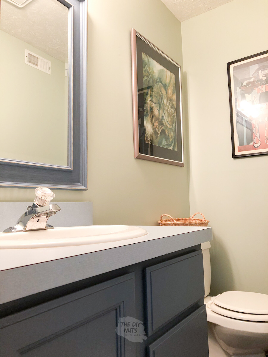 SW 6176 in small basement bathroom with painted oak bathroom cabinets with blue laminate countertops.