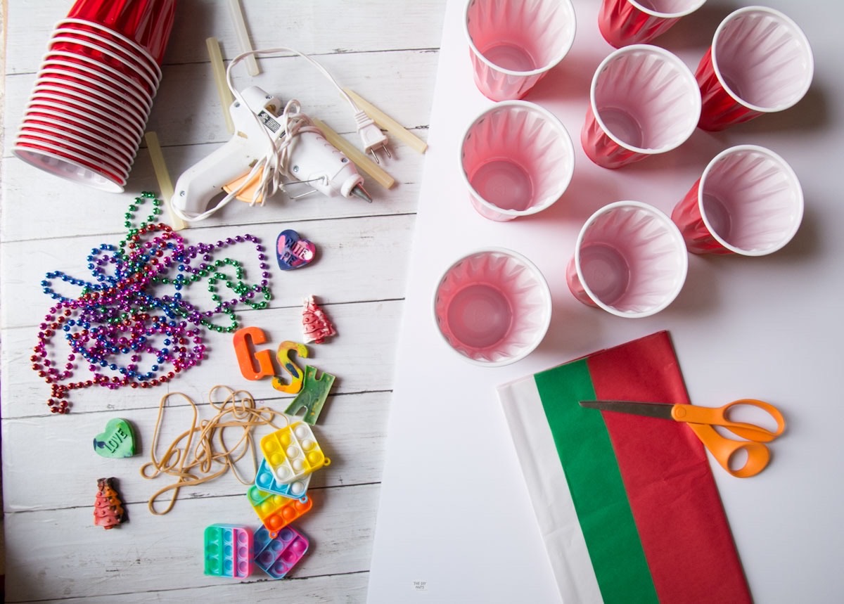 red plastic cups, tissue paper, scissors, glue gun and prizes with white board.
