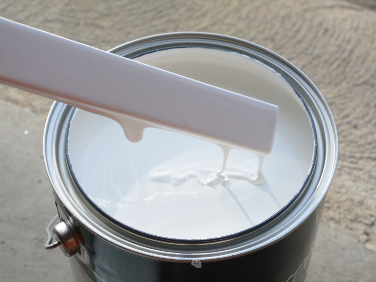 can of white paint with paint stick dipped in.