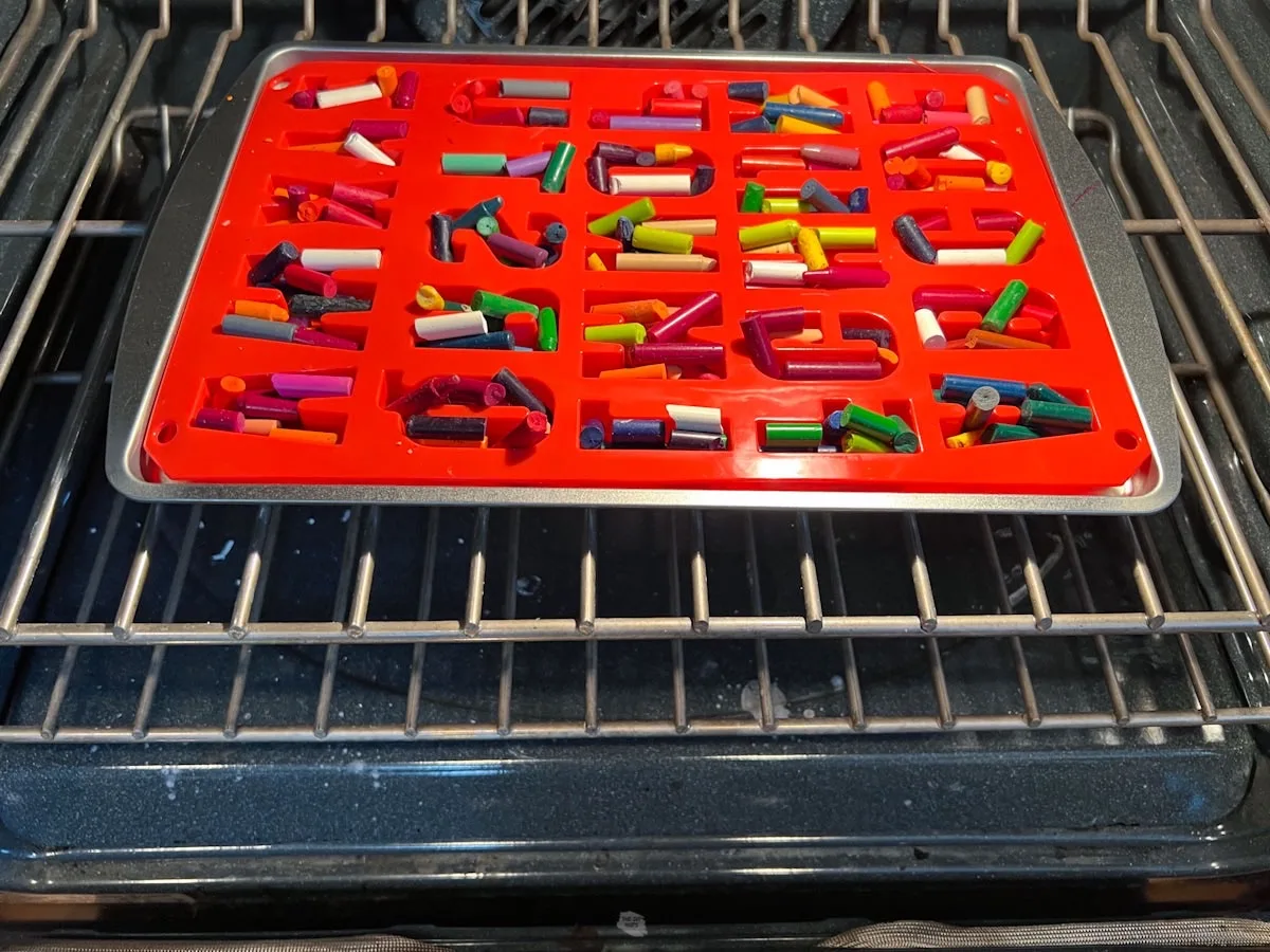 letter mold with crayons in oven on baking sheet.