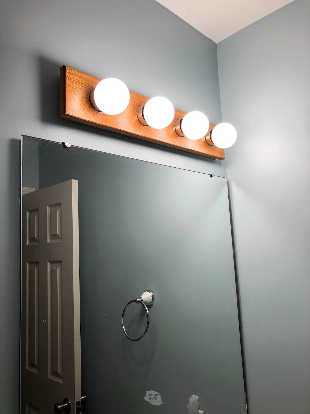 globe oak bathroom light fixture over construction grade mirror.