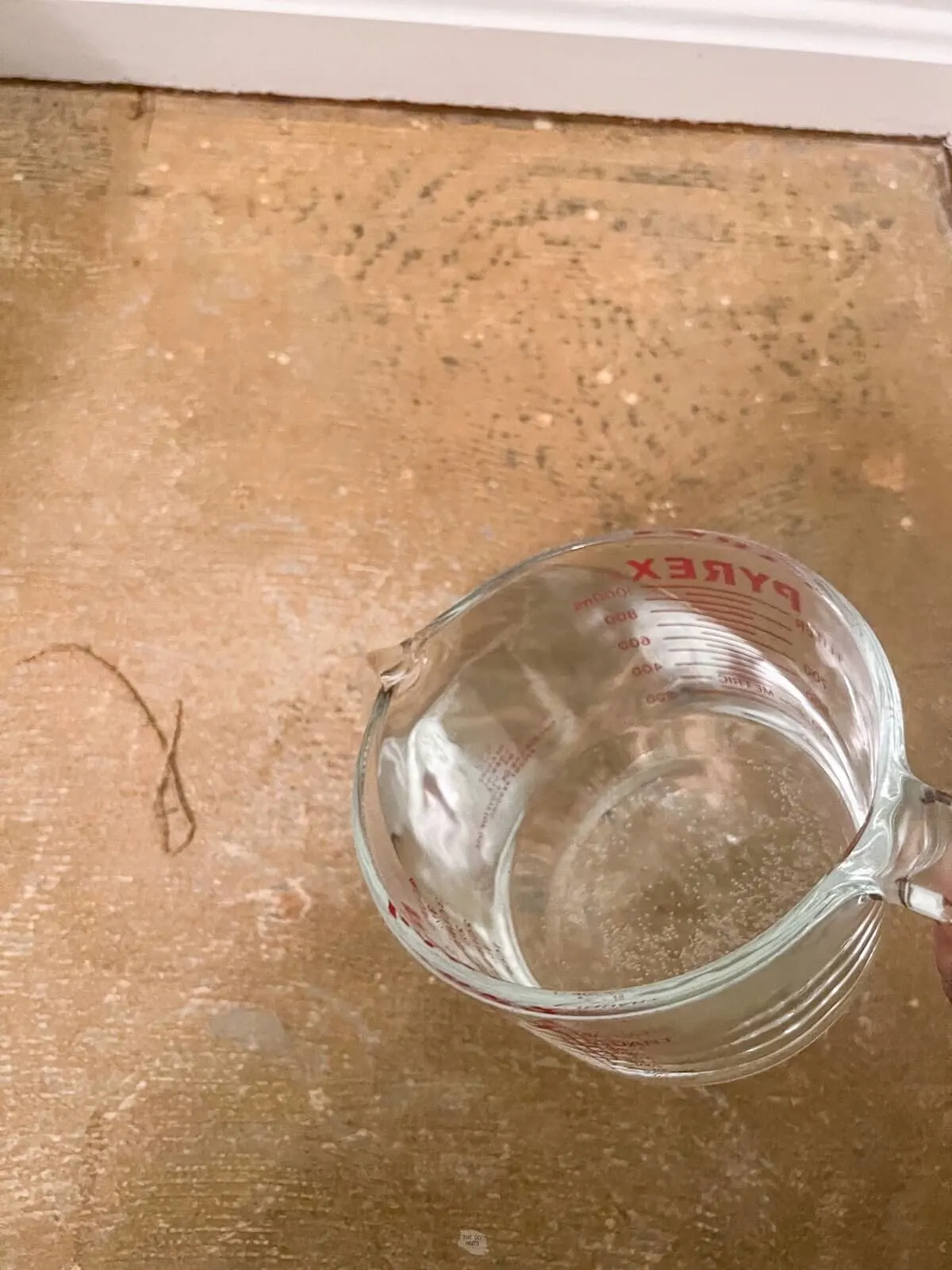 boiling water in glass measure cup being poured onto carpet glue on concrete.
