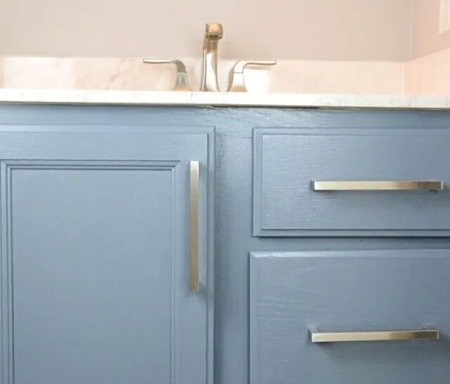 blue gray painted bathroom cabinet with silver handles and faucet.