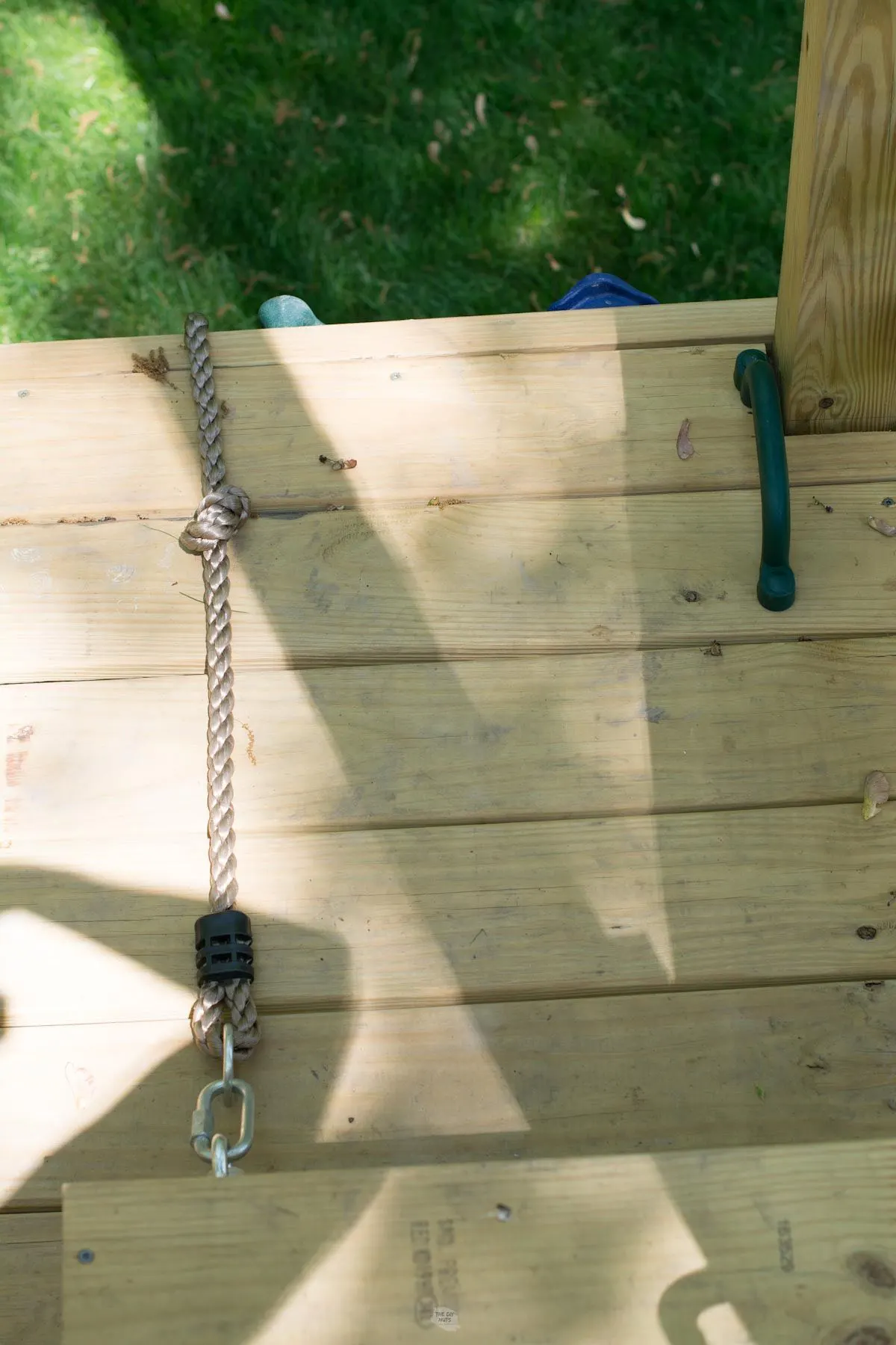 decking boards on platform of diy playground with handle and rope attached.