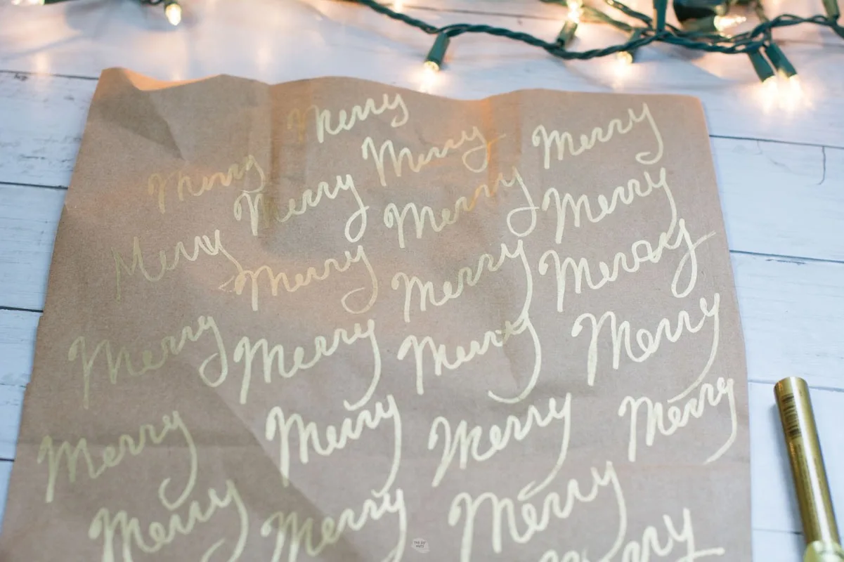 merry repeated in gold marker across opened brown bag paper.