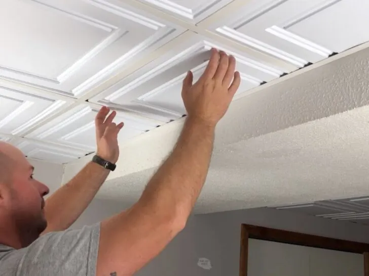 Man installing Ceilume Drop Ceiling Tiles in basement.