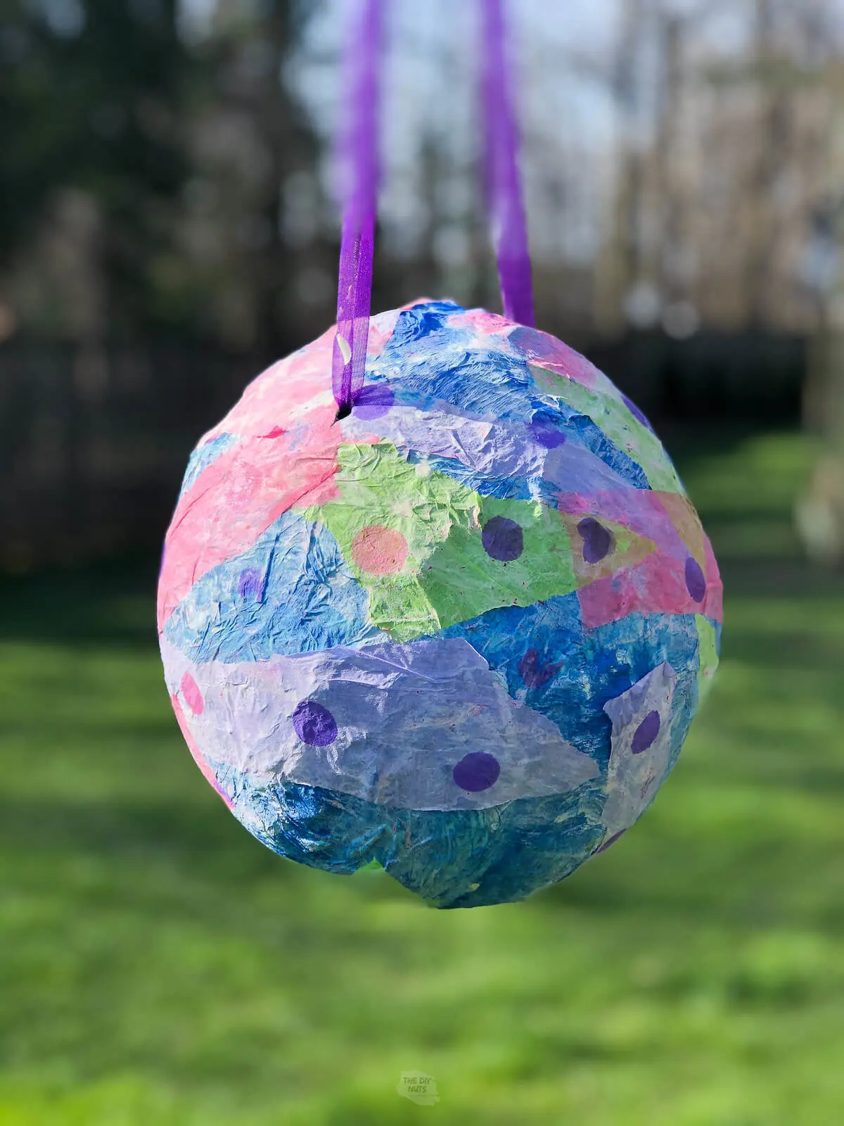 colorful piñata made from a balloon hanging outside.