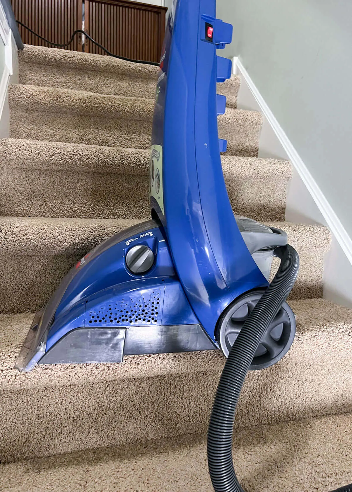 upright Bissel Steam cleaner on steps with hose attachment.