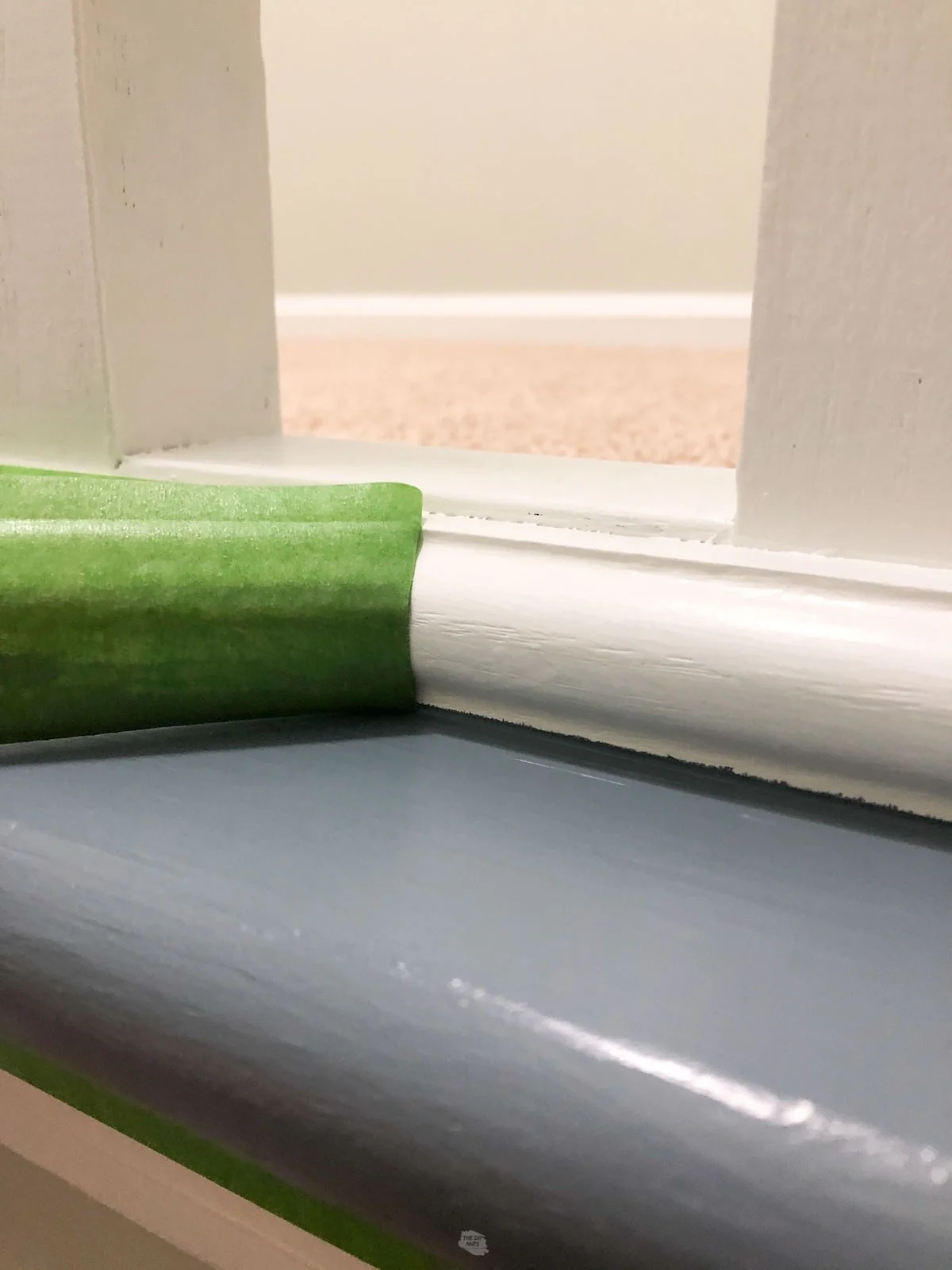 green painter's tape being pulled off bottom of stair railing.