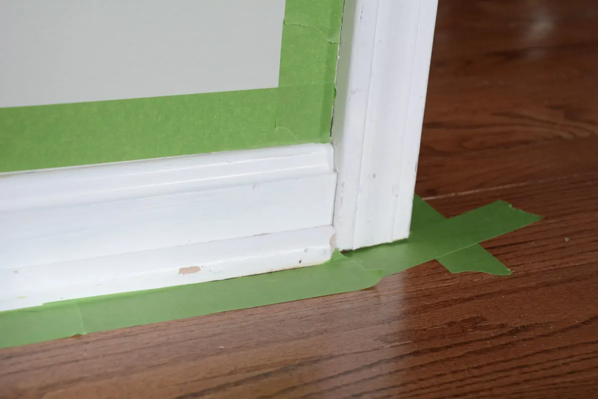 green painter's tape around white chipped painted molding.