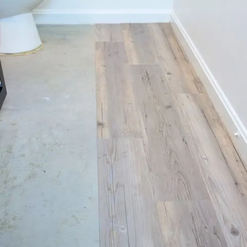 diy peel and stick wood tiles on half of bathroom floor.
