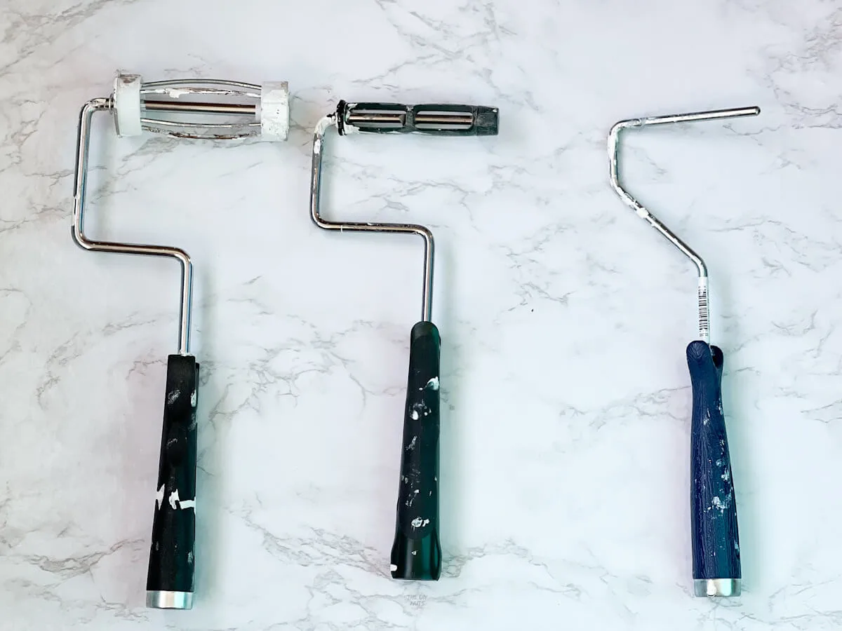 3 different mini paint roller handles on marble background.