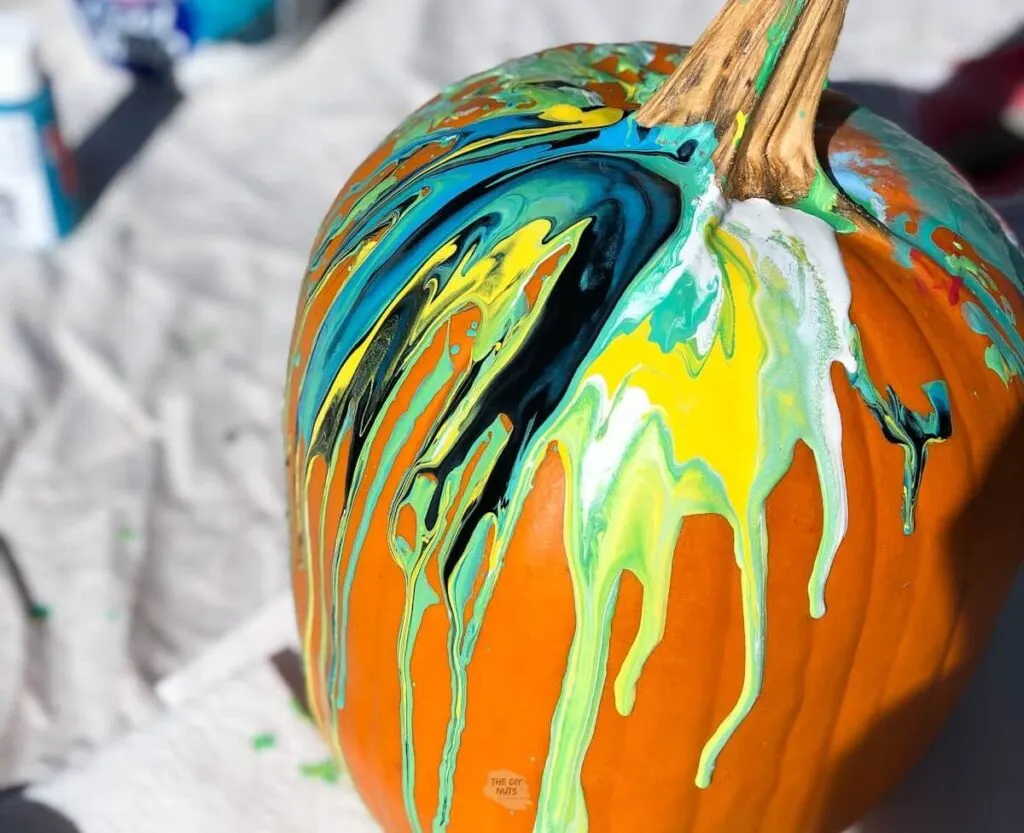 marbled colored painted poured on a pumpkin.