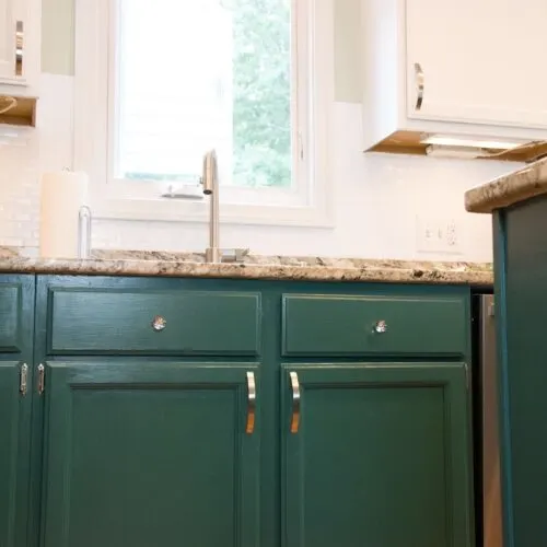 green lower kitchen cabinets and white upper cabinets by kitchen sink.
