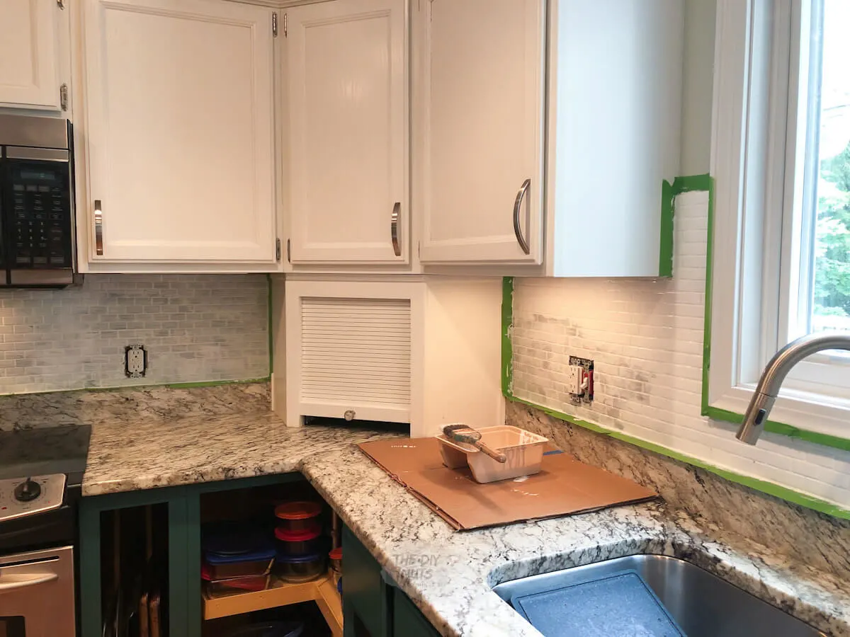 glass tile kitchen backsplash being painted in budget kitchen remodel idea.